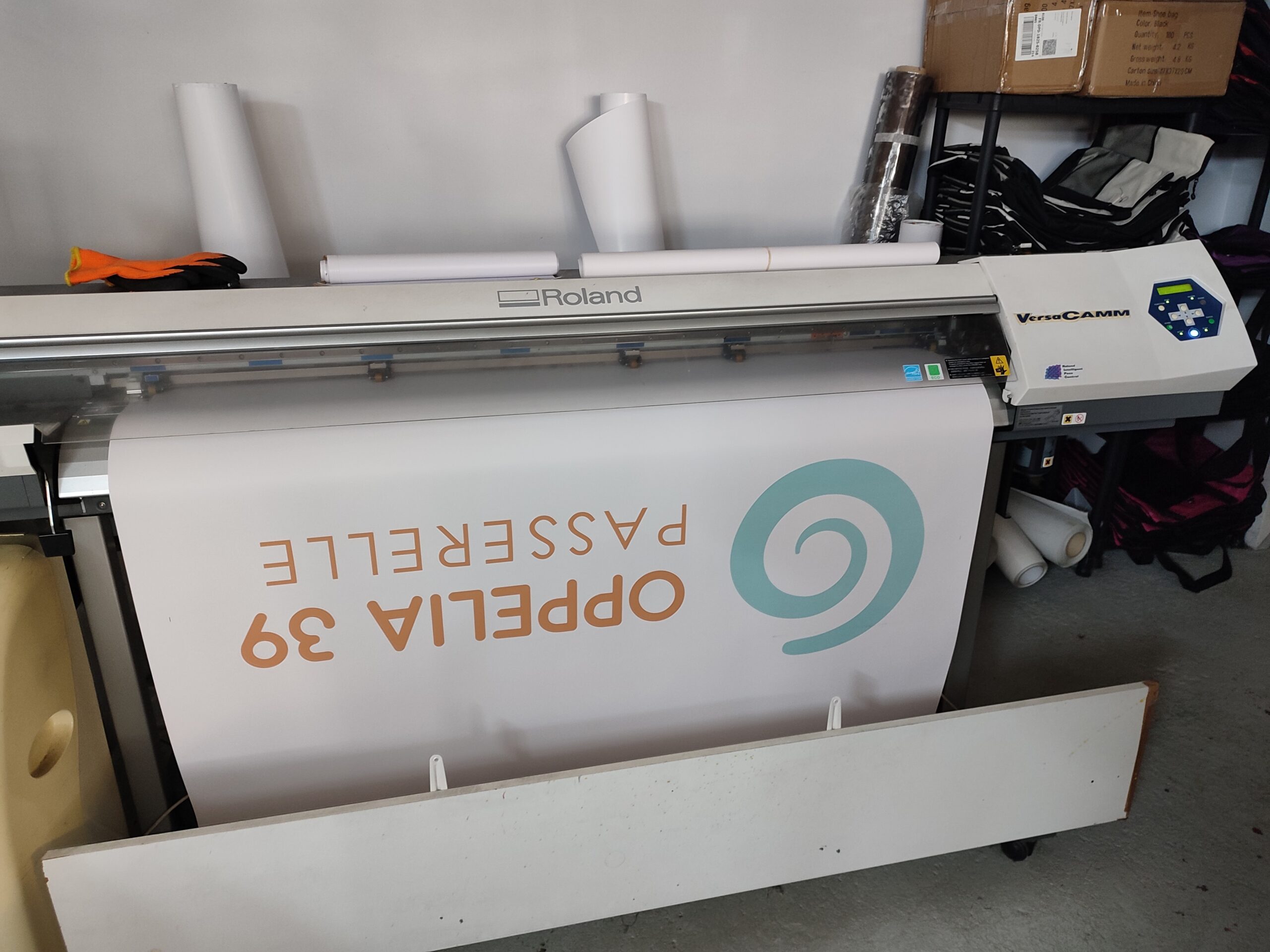Traceur d'impression grand format Roland VersaCAMM imprimant un adhésif Oppelia 39 dans l'atelier Swaag Shirt