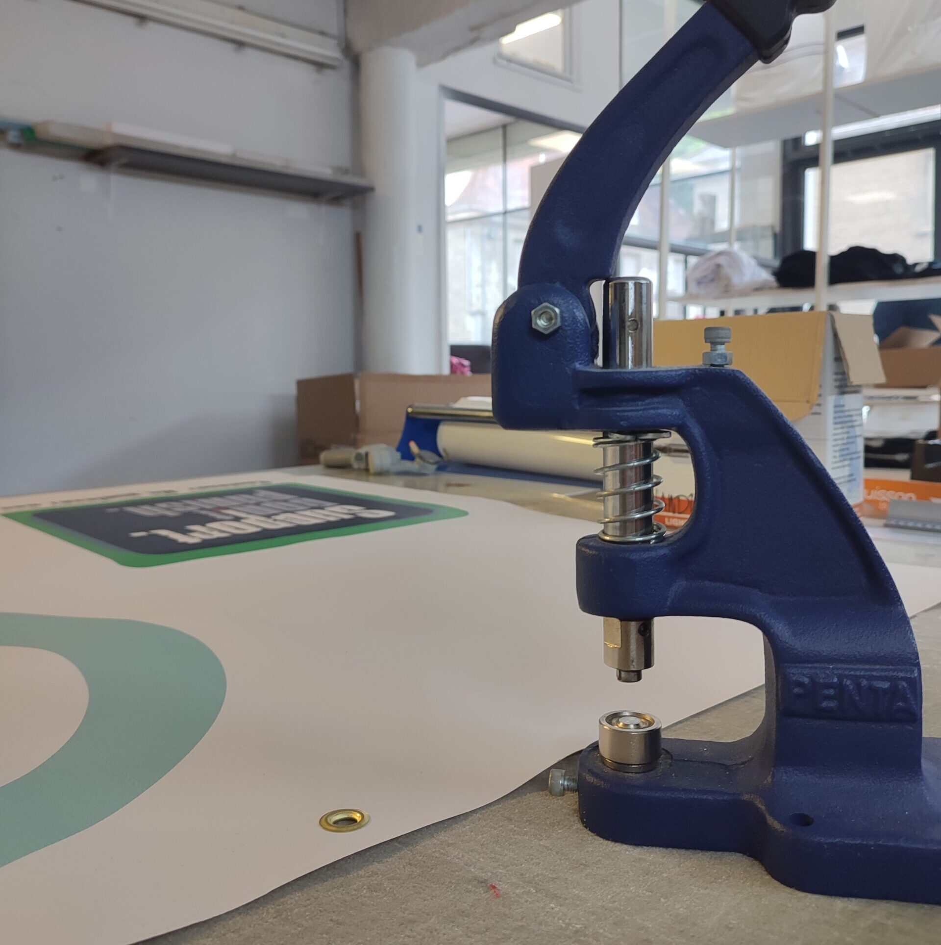 Pose d'œillets sur une banderole grand format imprimée dans l'atelier Swaag Shirt