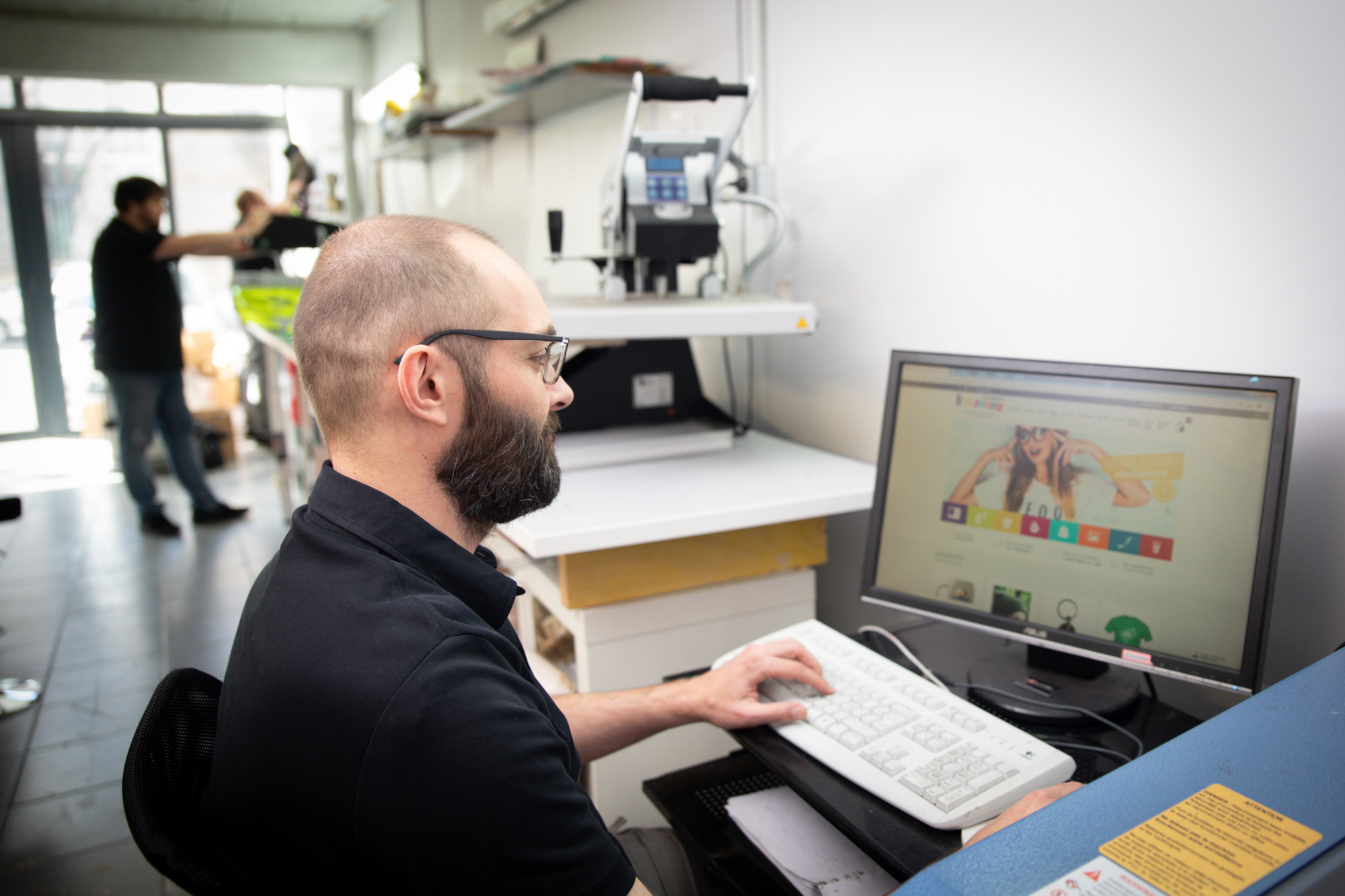 Membre de l'équipe Swaag Shirt travaillant sur un visuel à l'ordinateur dans l'atelier